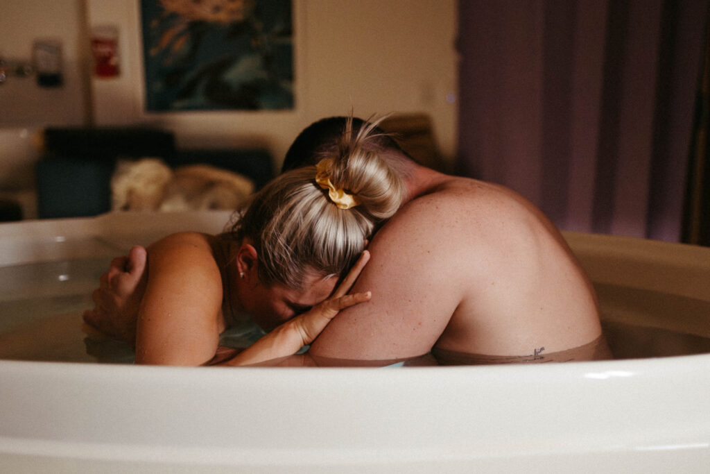 A husband and wife in the birthing bath getting ready to give birth