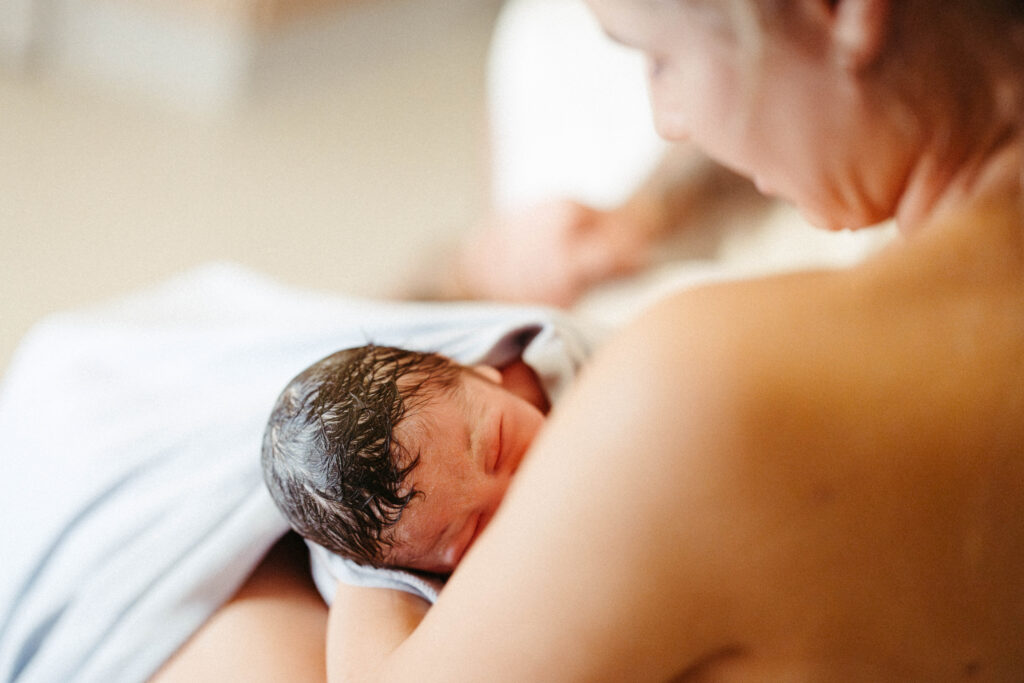 a woman feeding her son for the first time after birth