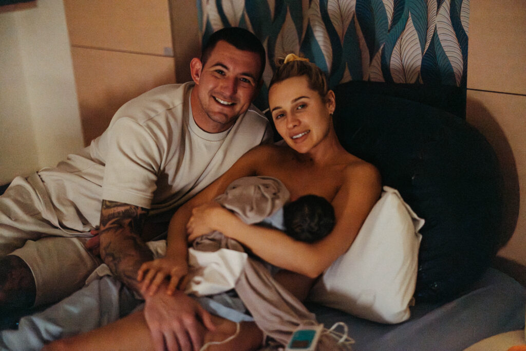 a woman just gave birth and she's holding her baby with her husband next to her 