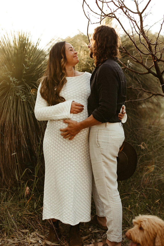 A pregnant woman with her husband and dog on a maternity shoot in the bush 