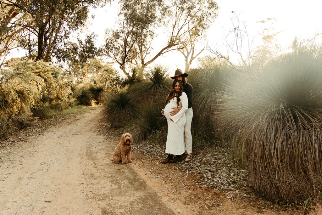 A pregnant woman with her partner and dog in the bush on a maternity photoshoot