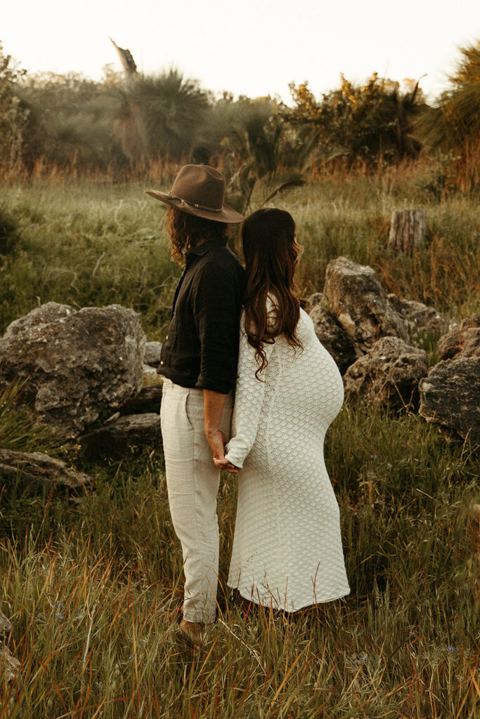 A pregnancy woman with her partner in a green field on a maternity photoshoot