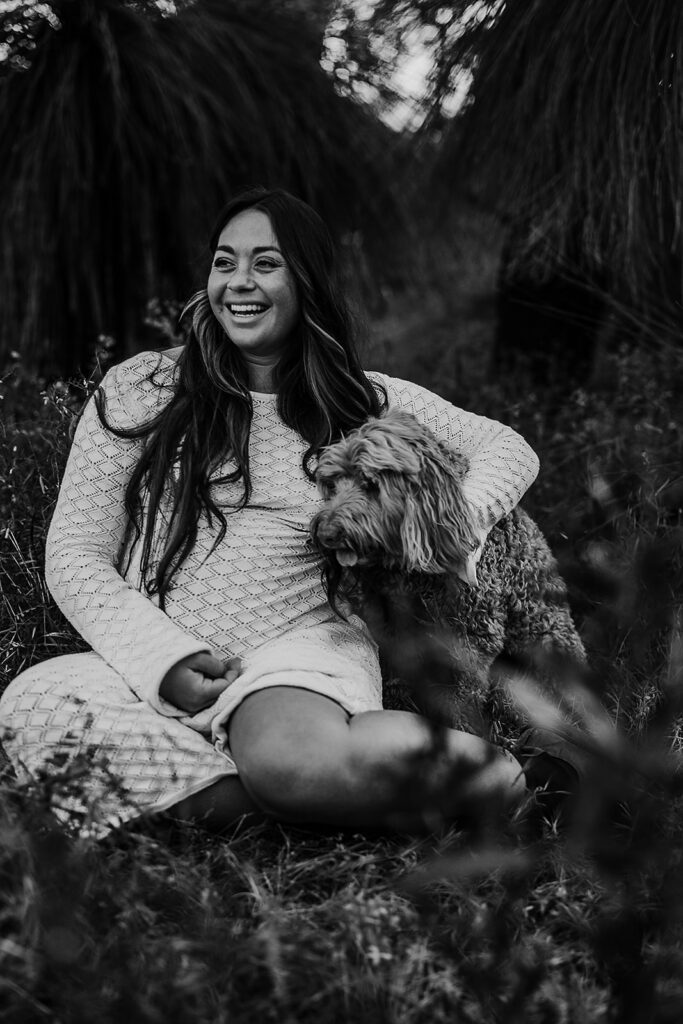 An expecting mother and dog in a field on a maternity shoot